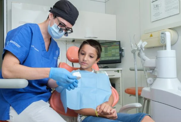 Un dentista spiega la cura dei denti a un bambino con un modellino